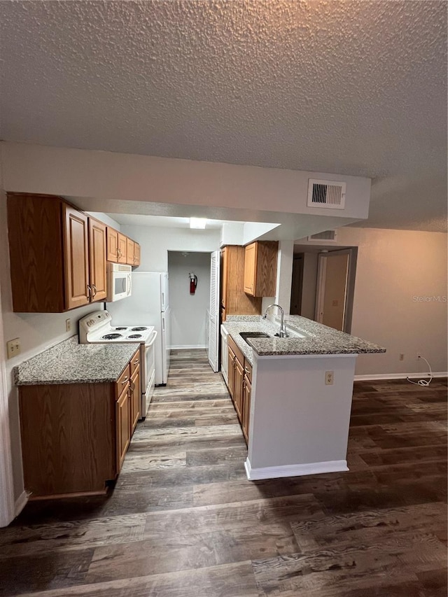 kitchen with kitchen peninsula, white appliances, sink, light stone countertops, and hardwood / wood-style flooring