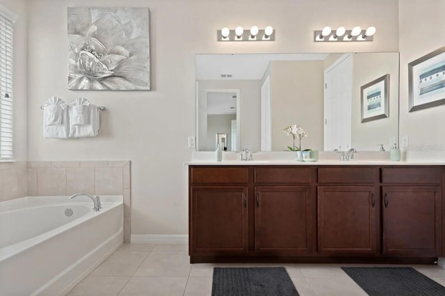 bathroom with a bathtub, double sink vanity, and tile patterned flooring