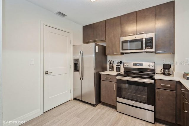 kitchen featuring dark brown cabinetry, stainless steel appliances, and light hardwood / wood-style flooring