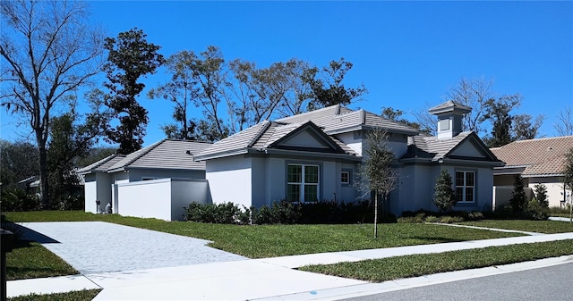 view of front facade with a tiled roof, a front yard, driveway, and stucco siding