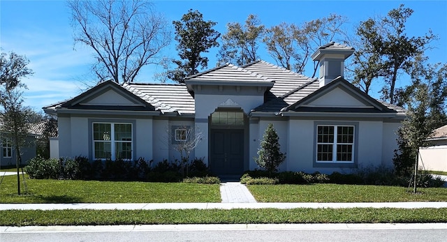 view of front of home featuring stucco siding, a front lawn, and a tiled roof