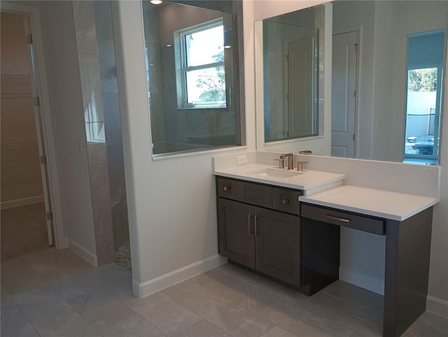 bathroom featuring a spacious closet, vanity, baseboards, and walk in shower