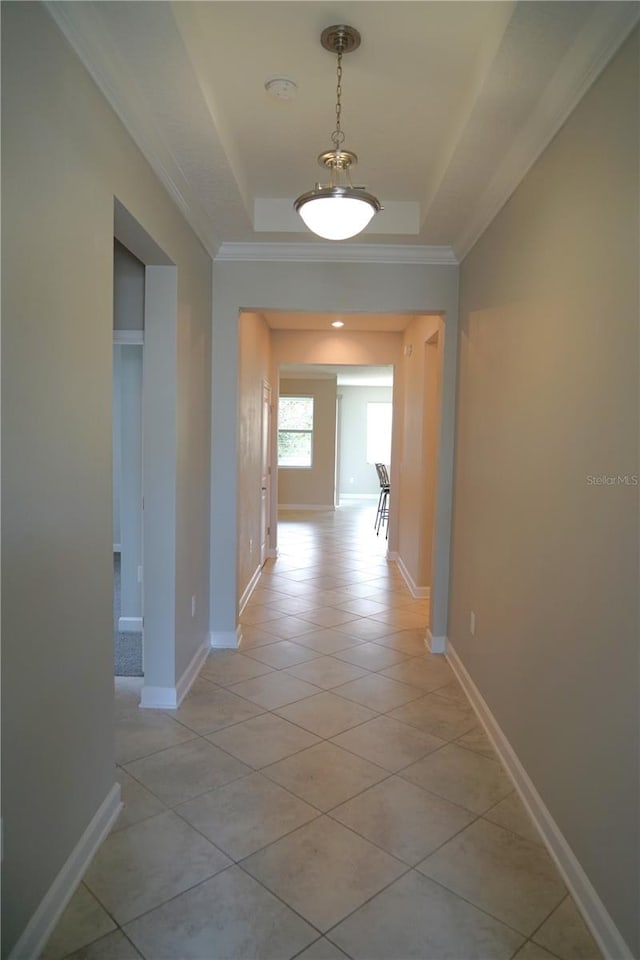 hall featuring light tile floors, a raised ceiling, and ornamental molding