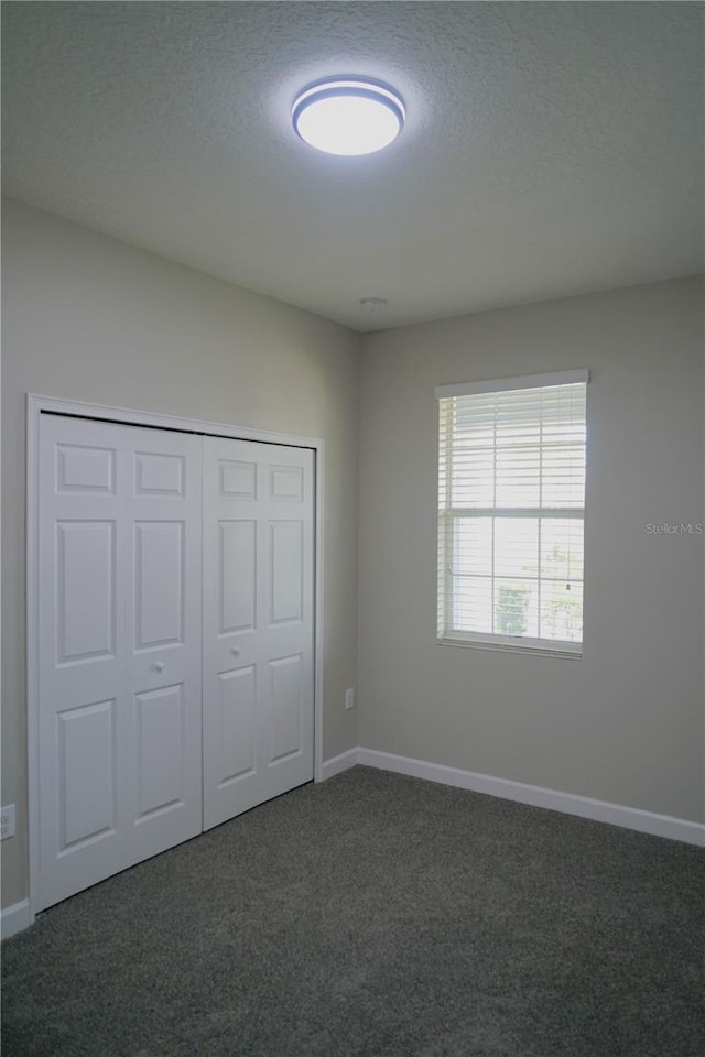 unfurnished bedroom with a closet and dark carpet