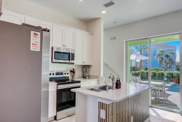 kitchen featuring an island with sink, sink, light tile floors, white cabinets, and appliances with stainless steel finishes