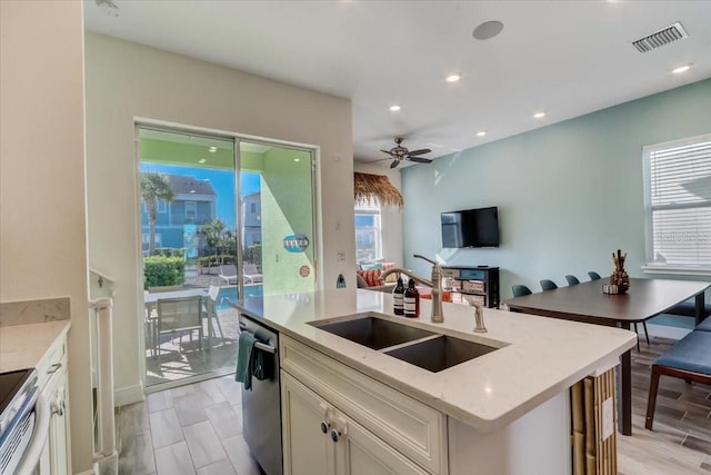 kitchen with stainless steel dishwasher, light stone counters, ceiling fan, and sink