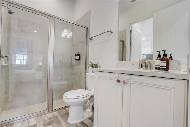 bathroom featuring toilet, vanity with extensive cabinet space, walk in shower, and wood-type flooring