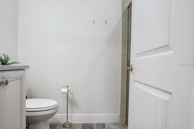 bathroom featuring toilet, a shower with door, hardwood / wood-style floors, and vanity