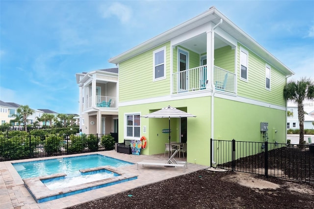 back of property featuring a pool with hot tub, a balcony, and a patio area