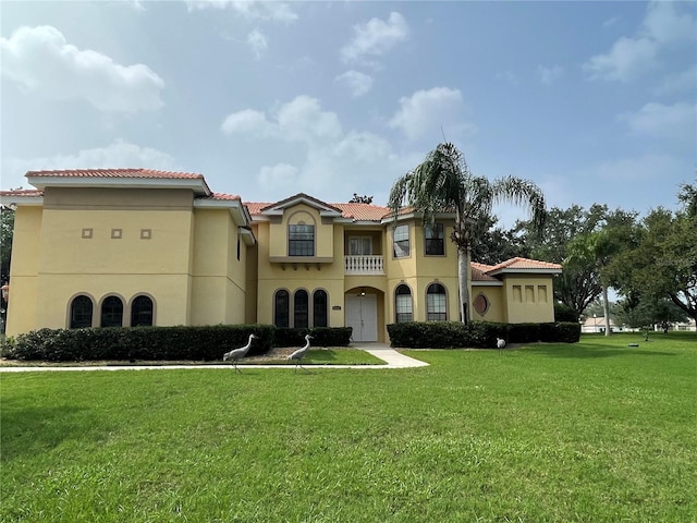 mediterranean / spanish-style home with a balcony and a front lawn