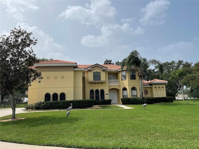 mediterranean / spanish home with a front yard and a balcony