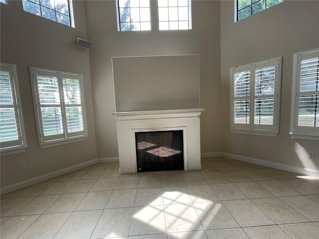 unfurnished living room with light tile floors and a towering ceiling