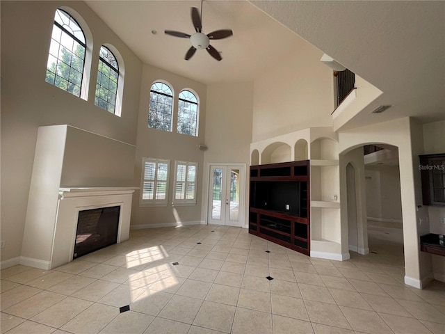 unfurnished living room with french doors, built in features, ceiling fan, and light tile floors