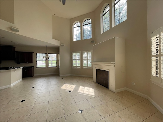 unfurnished living room with light tile floors, a notable chandelier, and a high ceiling