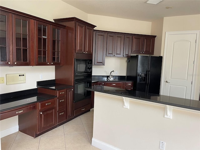 kitchen with light tile floors, a breakfast bar, black appliances, dark brown cabinetry, and sink