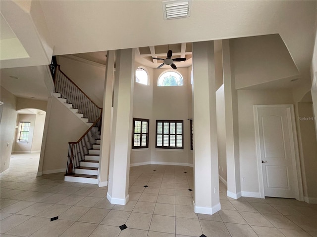 foyer with ceiling fan, light tile flooring, and a high ceiling