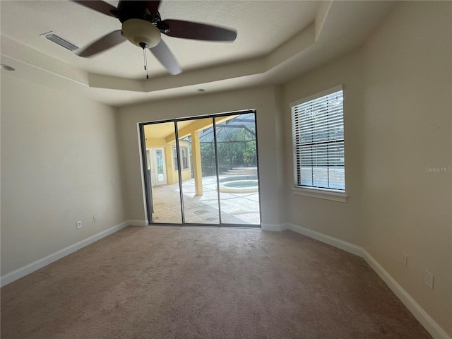 unfurnished room with light carpet, a raised ceiling, and ceiling fan