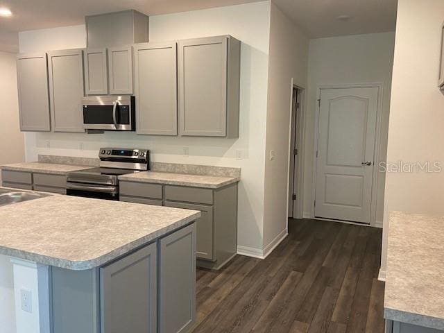 kitchen featuring gray cabinetry, a kitchen island, dark hardwood / wood-style floors, and appliances with stainless steel finishes