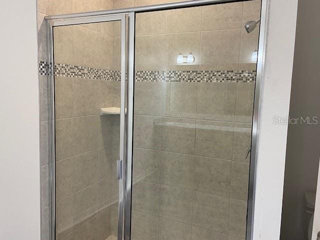 bathroom with toilet and a shower with shower door