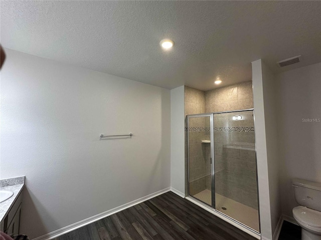 bathroom with hardwood / wood-style floors, vanity, a textured ceiling, toilet, and walk in shower