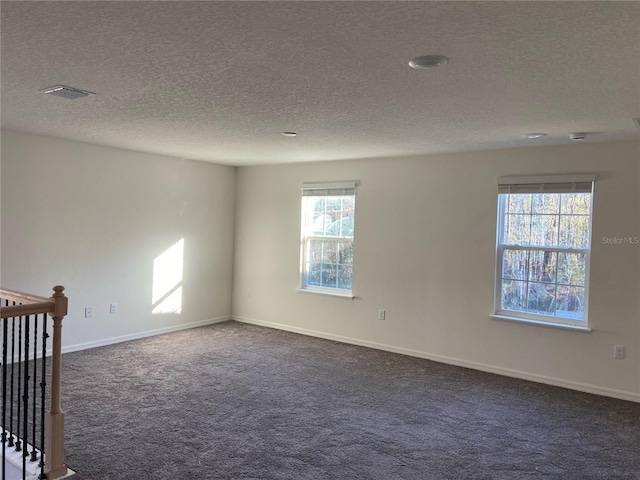 empty room with dark carpet and a textured ceiling