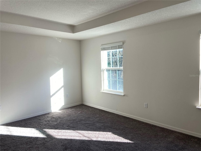 empty room featuring dark carpet and a textured ceiling