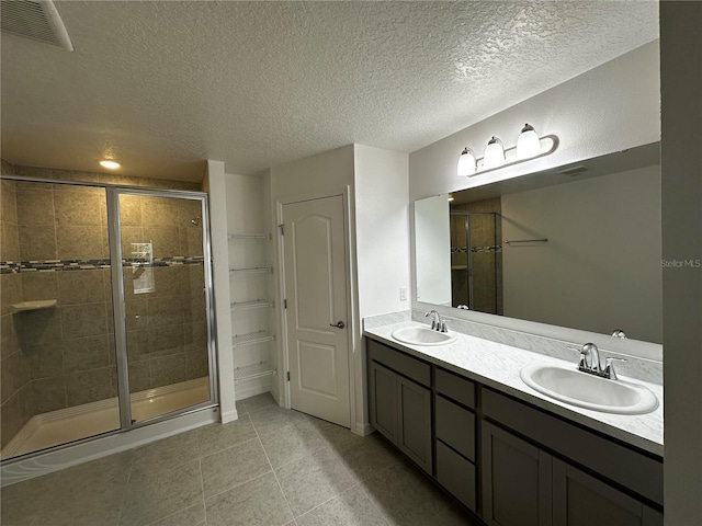 bathroom with tile patterned flooring, vanity, a shower with door, and a textured ceiling