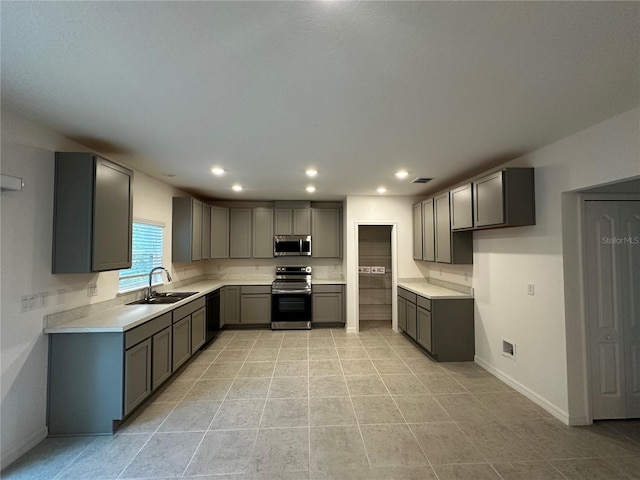 kitchen with gray cabinetry, sink, light tile patterned floors, and appliances with stainless steel finishes