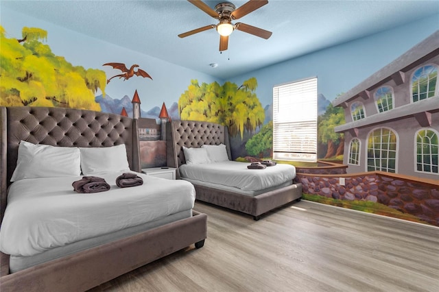 bedroom with a textured ceiling, ceiling fan, and light wood-type flooring