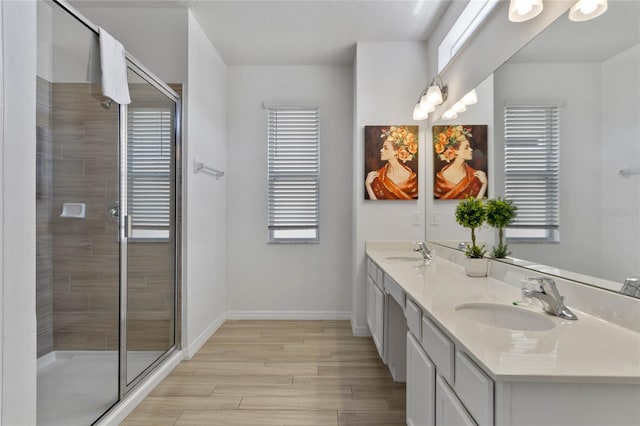 bathroom featuring double sink, a shower with shower door, vanity with extensive cabinet space, and wood-type flooring