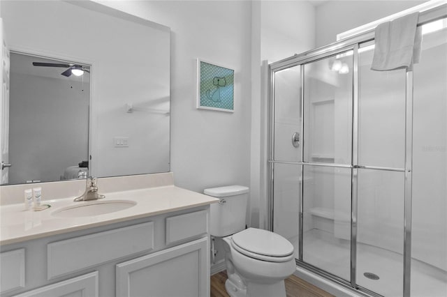 bathroom featuring walk in shower, ceiling fan, wood-type flooring, toilet, and large vanity