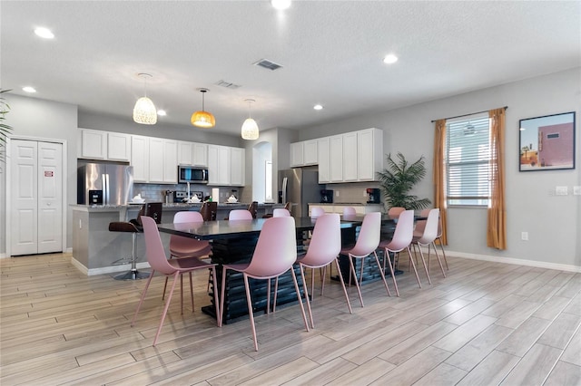 dining space featuring light hardwood / wood-style floors and a textured ceiling