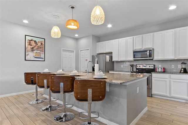 kitchen featuring white cabinets, pendant lighting, tasteful backsplash, and appliances with stainless steel finishes