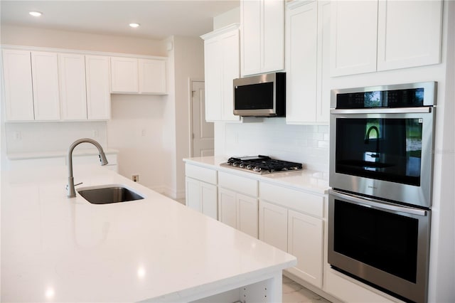 kitchen featuring stainless steel appliances, white cabinetry, sink, and tasteful backsplash