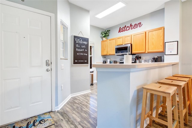 kitchen with a kitchen breakfast bar, light brown cabinets, and light hardwood / wood-style flooring