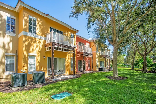 rear view of house featuring a balcony, central air condition unit, and a lawn