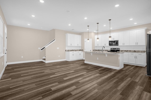 kitchen featuring stainless steel appliances, decorative light fixtures, and dark hardwood / wood-style flooring