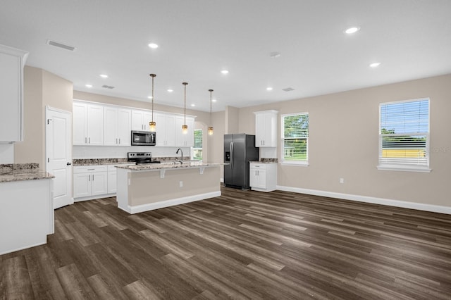 kitchen featuring decorative light fixtures, white cabinetry, stainless steel appliances, a center island with sink, and dark hardwood / wood-style flooring