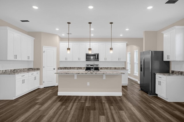 kitchen featuring white cabinetry, appliances with stainless steel finishes, dark wood-type flooring, and a center island with sink