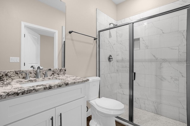 bathroom featuring toilet, a shower with shower door, and vanity with extensive cabinet space