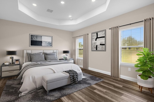 bedroom featuring a tray ceiling and dark wood-type flooring