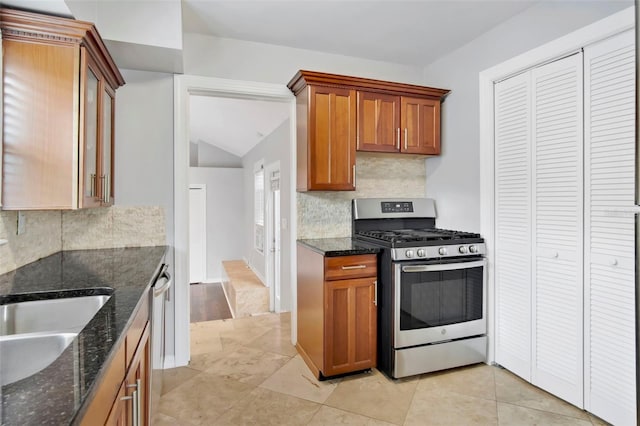 kitchen with backsplash, dark stone countertops, light tile floors, and appliances with stainless steel finishes