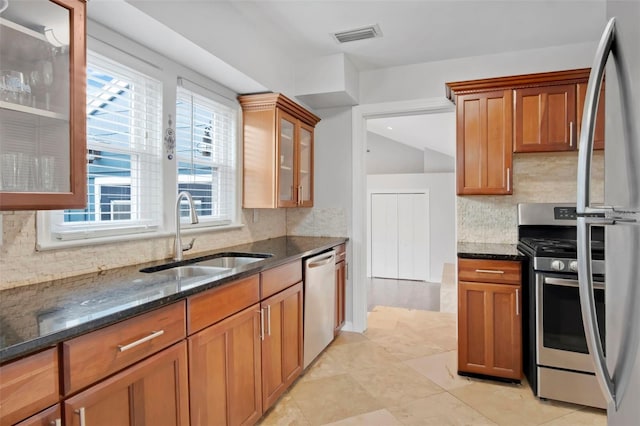 kitchen featuring light tile floors, backsplash, dark stone countertops, and stainless steel appliances