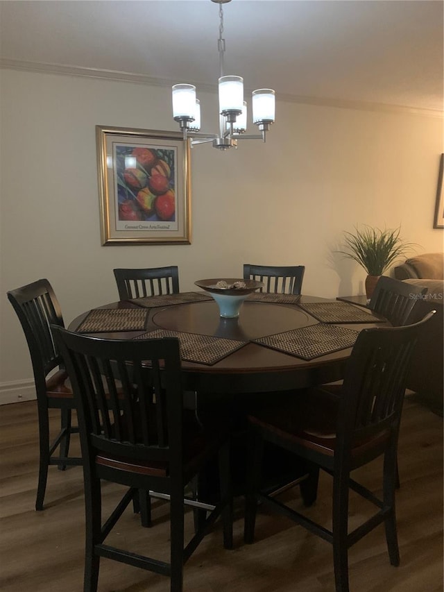 dining area with a chandelier, dark wood-type flooring, and ornamental molding