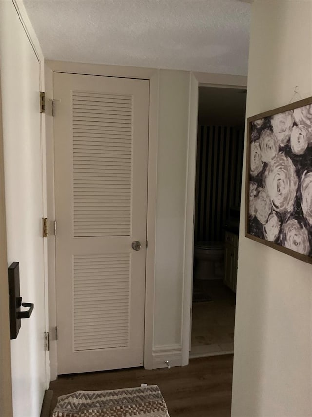 hall with a textured ceiling and dark hardwood / wood-style flooring