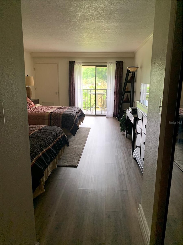 bedroom with a textured ceiling, crown molding, wood-type flooring, and access to exterior