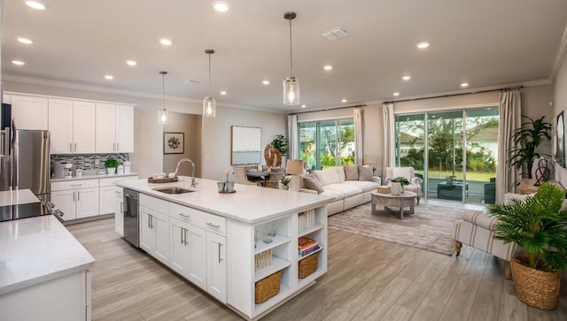 kitchen with white cabinetry, sink, light stone counters, and decorative light fixtures