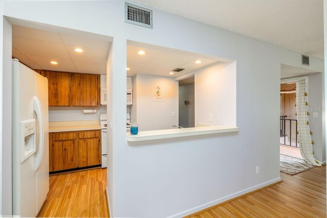 kitchen with light hardwood / wood-style floors, white appliances, and a paneled ceiling