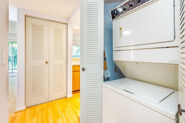 laundry area with light hardwood / wood-style flooring and stacked washer and dryer