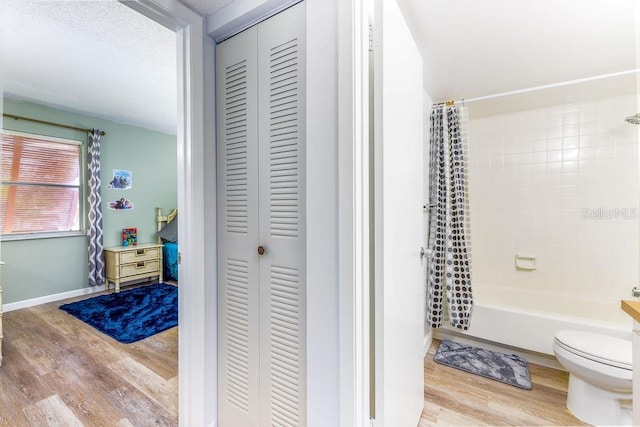 bathroom with shower / tub combo, toilet, and hardwood / wood-style flooring